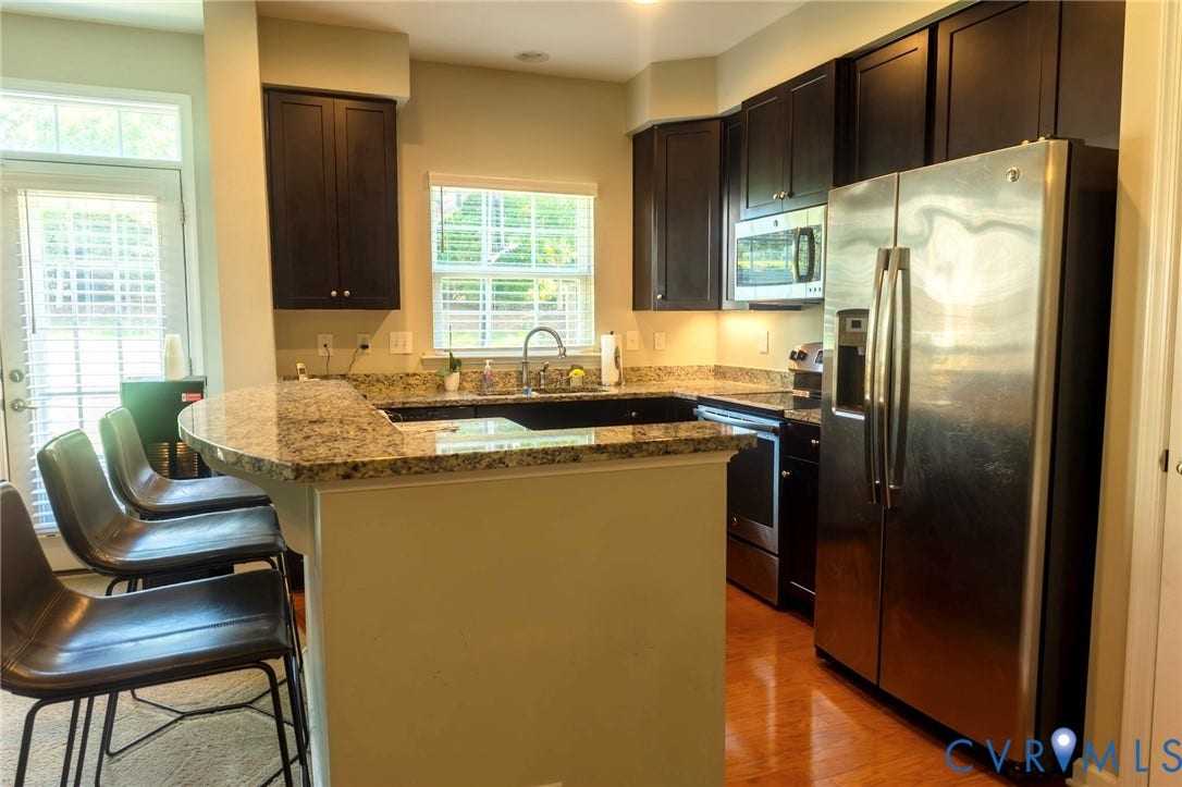 11617 Vicars Ridge Lane, Glen Allen, VA 23059 Kitchen featuring dark wood cabinetry, stainless steel appliances, granite countertops, wood-finish flooring, and a breakfast bar