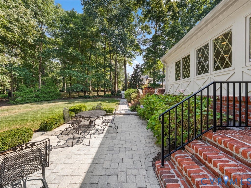 500 Kilmarnock Drive, Collegiate Area, Henrico, VA 23229 Expansive backyard featuring a manicured lawn, paver patio, brick steps with a black metal railing, and diamond-pane windows