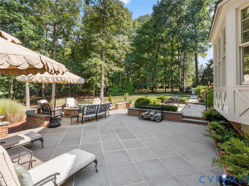 500 Kilmarnock Drive, Collegiate Area, Henrico, VA 23229 Expansive stone patio featuring a built-in brick fire pit, a curved brick retaining wall, and mature landscaping