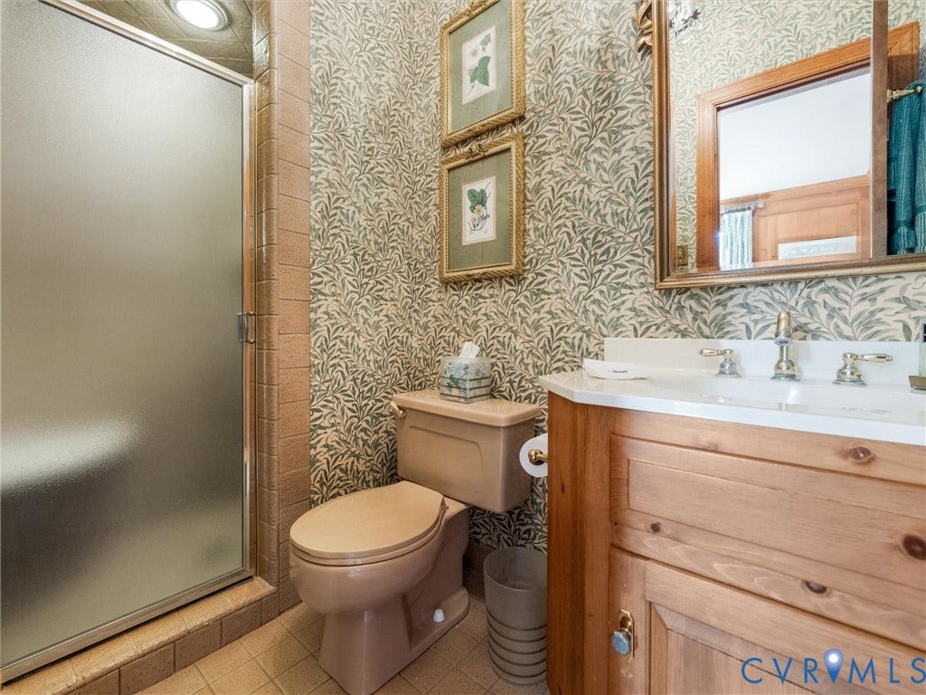 500 Kilmarnock Drive, Collegiate Area, Henrico, VA 23229 Frosted glass shower enclosure, single vanity with wood-finish cabinetry, white countertop, and dual-handle faucet