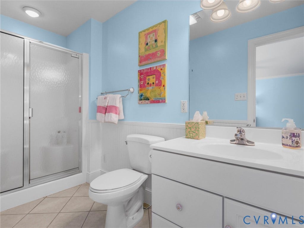 500 Kilmarnock Drive, Collegiate Area, Henrico, VA 23229 Shower with sliding frosted glass door, white vanity with integrated sink, chrome faucet, white beadboard wainscoting, and tile flooring
