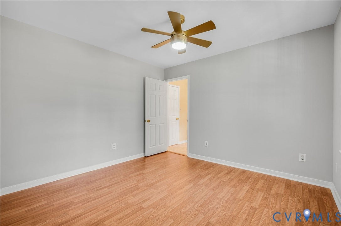 Wood-finish flooring with light gray wall paint and a ceiling fan with integrated lighting