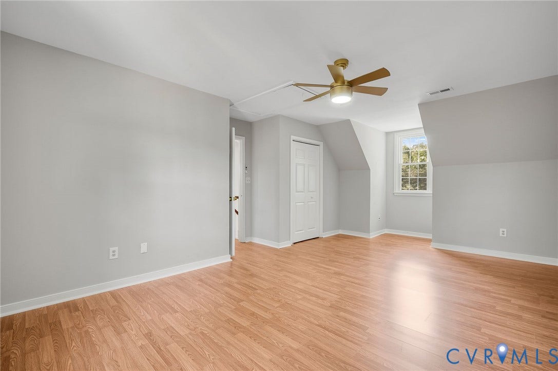 Wood-finish flooring, white walls, and a ceiling fan with integrated lighting