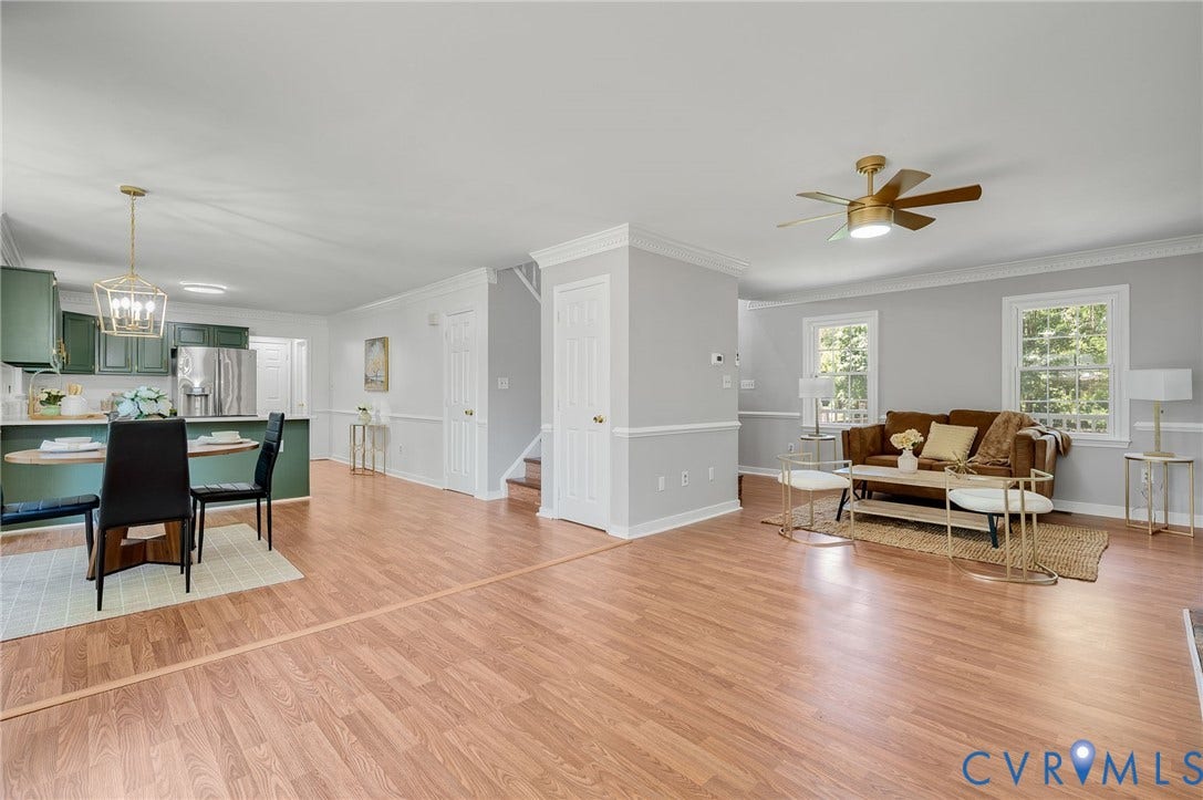 Wood-finish flooring throughout, kitchen with green cabinetry, stainless steel appliances, and a gold-tone pendant light fixture