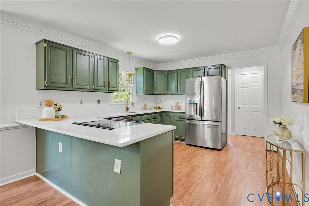Kitchen featuring green cabinetry, white countertops, wood-finish flooring, and a stainless steel refrigerator
