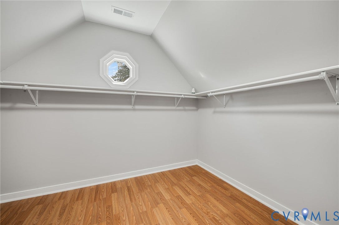 Wood-finish flooring, white walls, angled ceiling, and an octagonal window