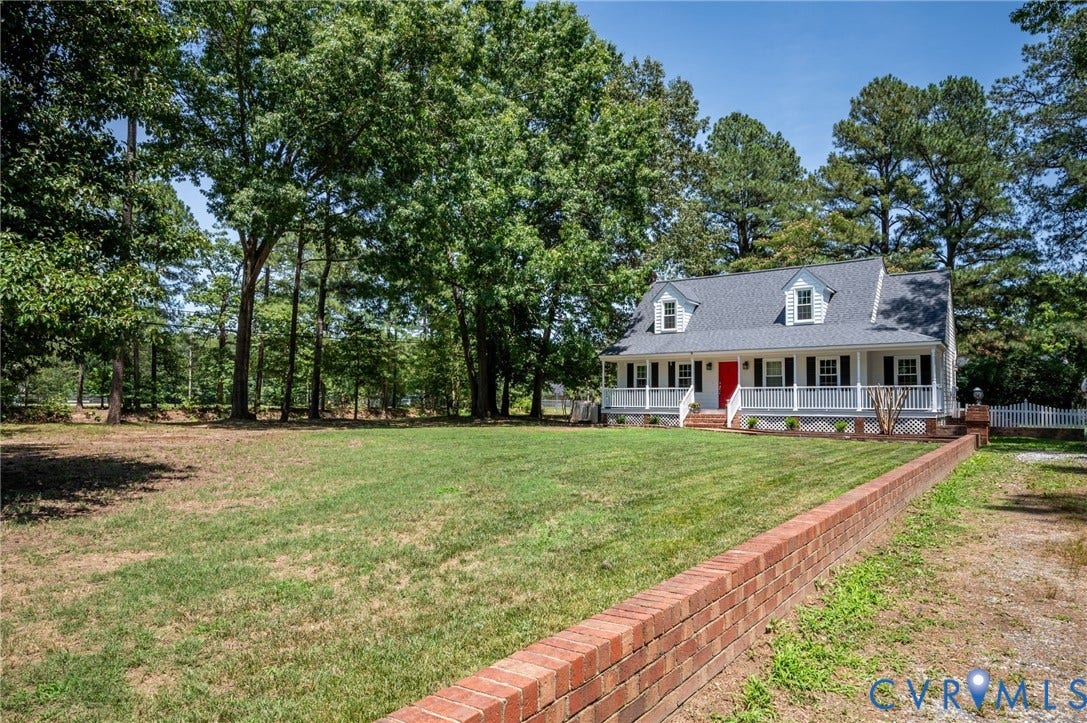 Gray siding exterior with white trim, red front door, and full-width porch featuring white railings