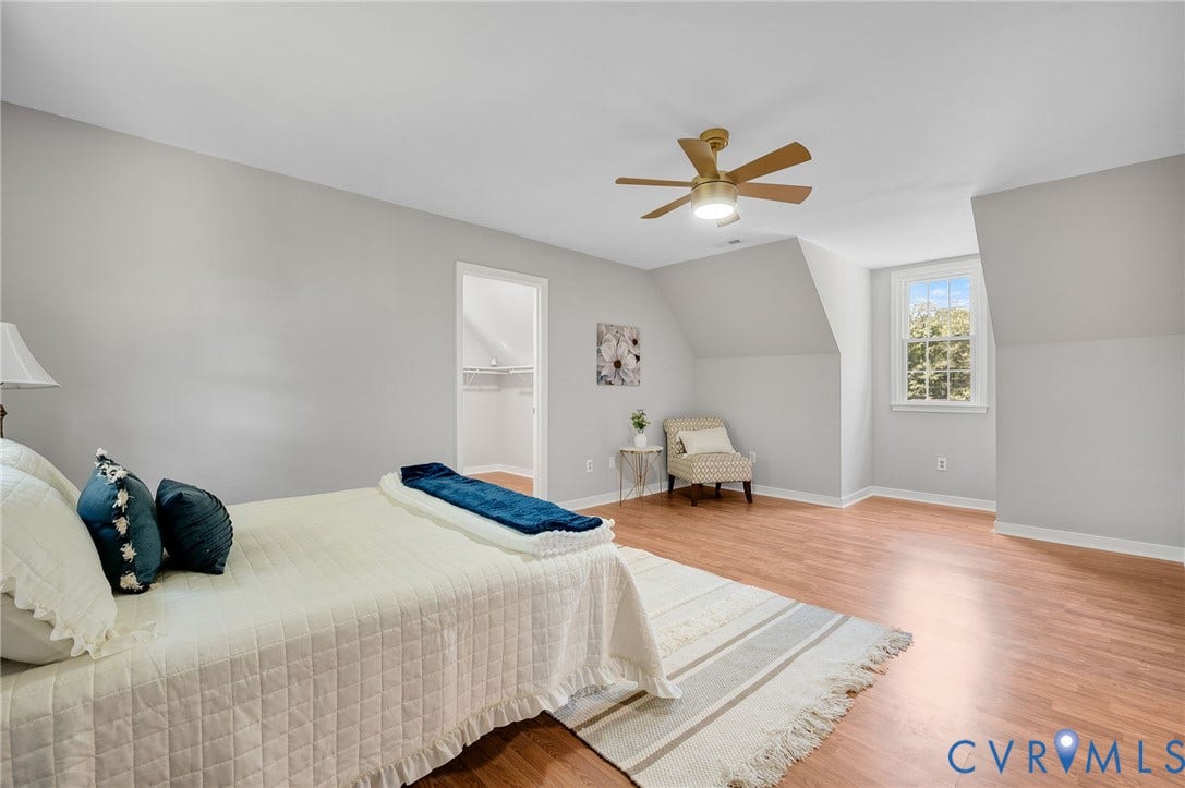 Spacious room featuring wood-finish flooring, a ceiling fan with integrated lighting, and sloped ceiling details