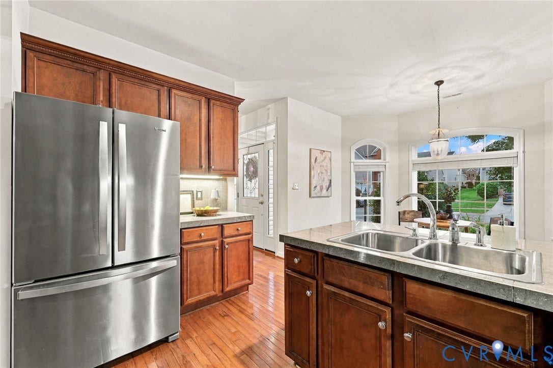 9619 Redwick Drive, Matoaca, Chesterfield, VA 23112 Kitchen featuring wood-finish flooring, wood cabinetry with crown molding, stainless steel refrigerator, and a double basin sink with a chrome faucet