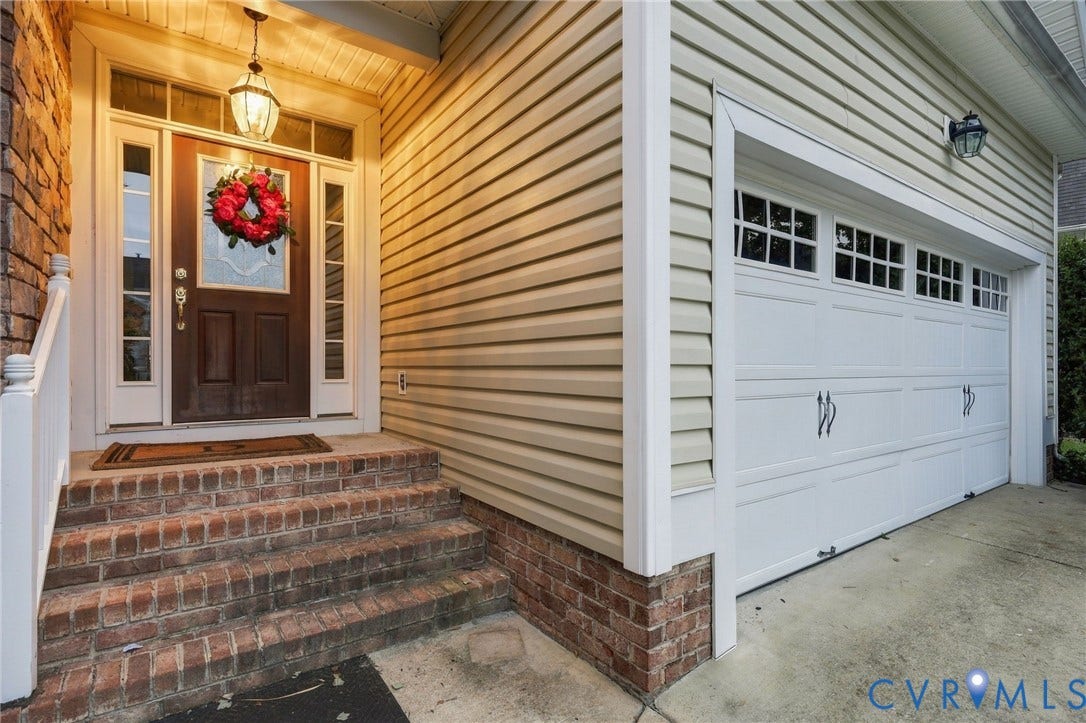 9619 Redwick Drive, Matoaca, Chesterfield, VA 23112 Brick stairs and foundation, wood-panel entry door with sidelights, overhead entry light fixture, and white paneled garage door with window inserts