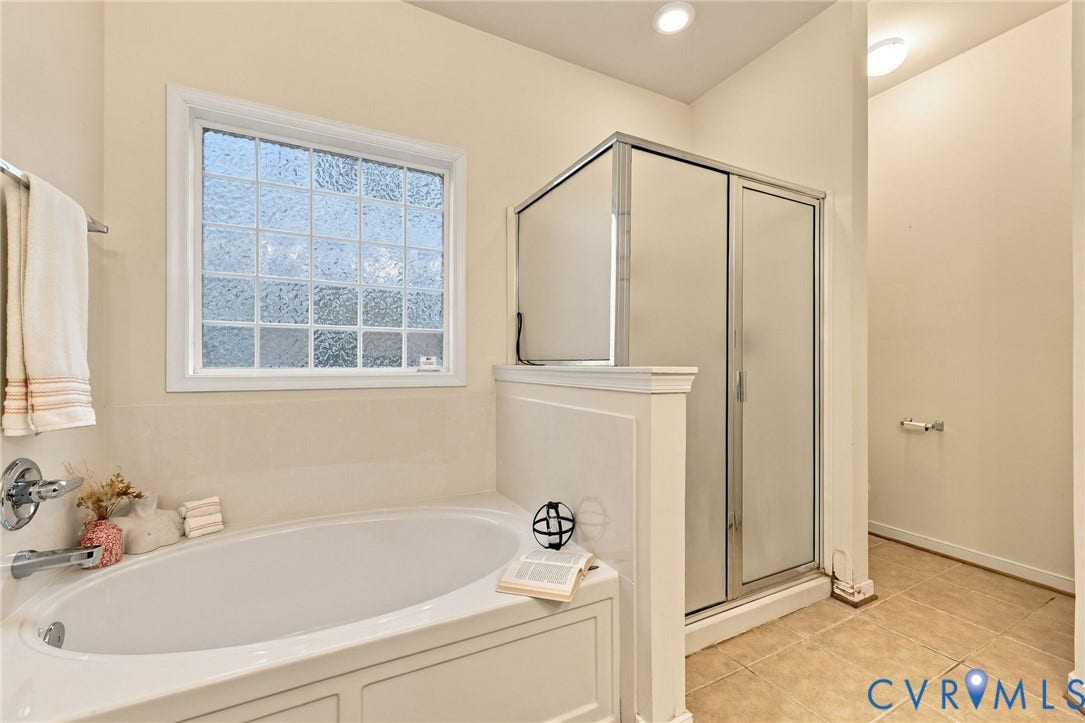 9619 Redwick Drive, Matoaca, Chesterfield, VA 23112 Soaking tub with a tiled surround, privacy glass window, and an enclosed shower with frosted panels and a metal frame
