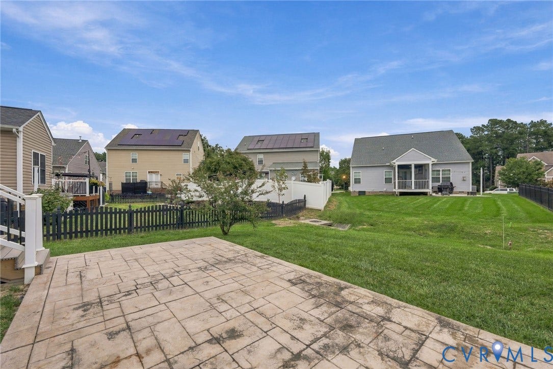 9619 Redwick Drive, Matoaca, Chesterfield, VA 23112 Expansive green space featuring a stamped concrete patio, a white vinyl fence, and a black picket fence