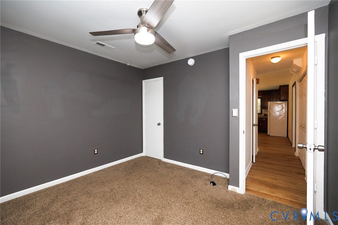 20520 Cox Road, Sutherland, VA 23885 Carpeted room with a ceiling fan light fixture and a white door