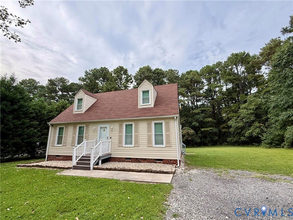 20520 Cox Road, Sutherland, VA 23885 Dormer windows, light-colored siding exterior, red-toned shingle roof, front porch with white railing, and a gravel driveway