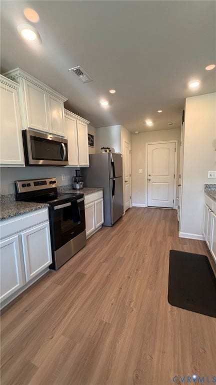 Kitchen featuring wood-finish flooring, recessed lighting, white cabinetry, and stainless steel appliances