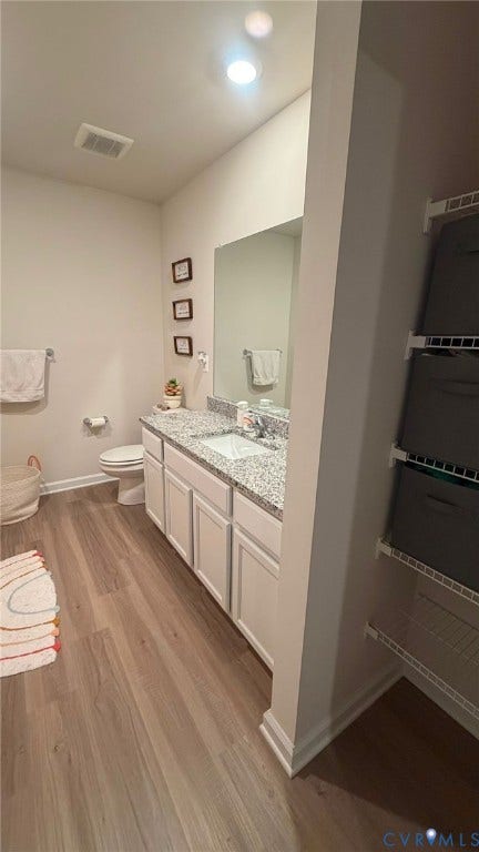 Vanity with undermount sinks, granite-style countertop, and white cabinetry