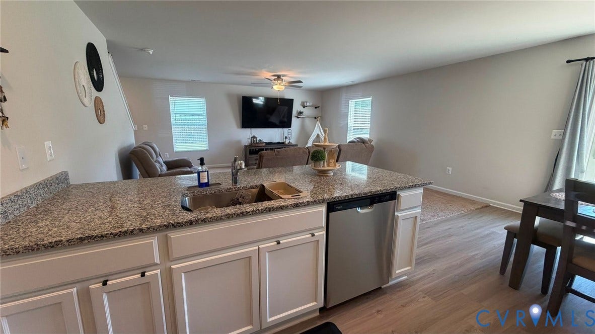 Kitchen island with granite-finish countertop, stainless steel sink, and stainless steel dishwasher
