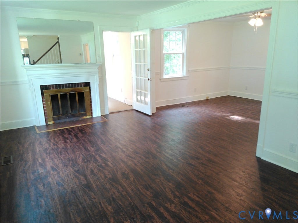 6902 Old Jahnke Road, Richmond, VA 23225 Wood-finish flooring throughout, featuring a white mantel fireplace with a brass firebox, French doors, and a window with white trim