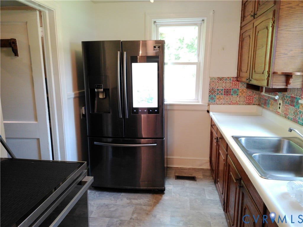 6902 Old Jahnke Road, Richmond, VA 23225 Kitchen featuring wood cabinetry, a double basin stainless steel sink, a patterned tile backsplash, and wood-finish flooring