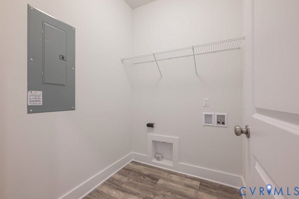 Utility area featuring wood-finish flooring, white walls, and a built-in wire shelf