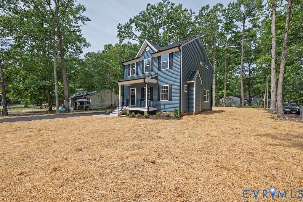 Blue siding exterior with white trim, covered front porch, dark shutters, and a gabled roof