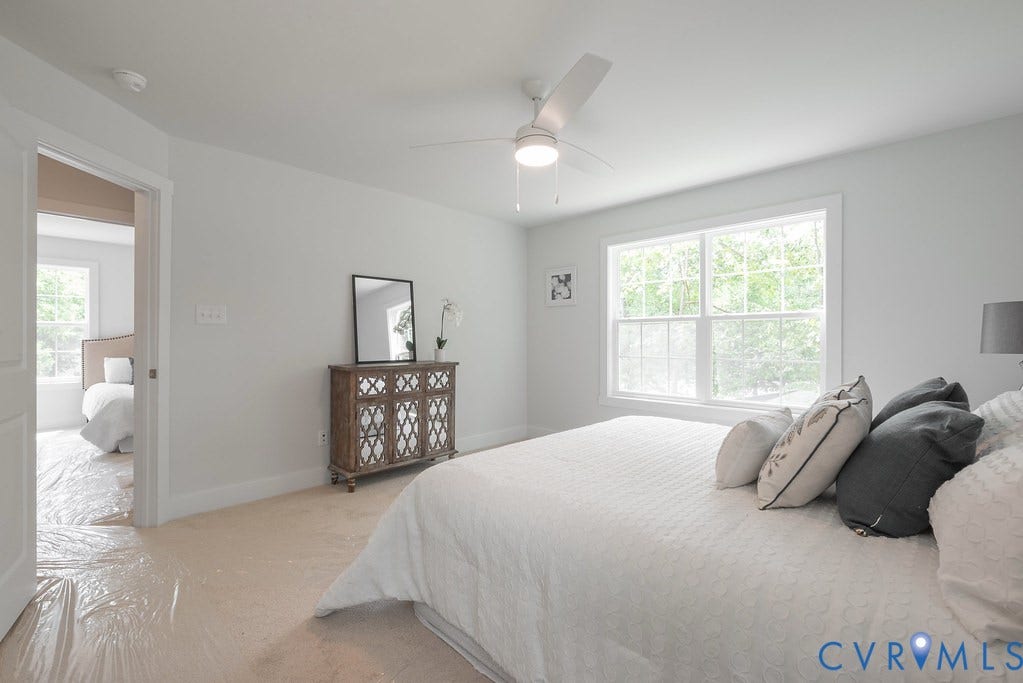 Light-filled room featuring a broad window, white painted walls, and a ceiling fan with integrated lighting