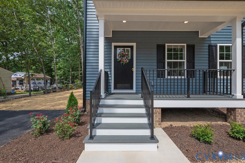 Inviting front porch with durable composite decking, black railings, and a contrasting black front door with decorative glass