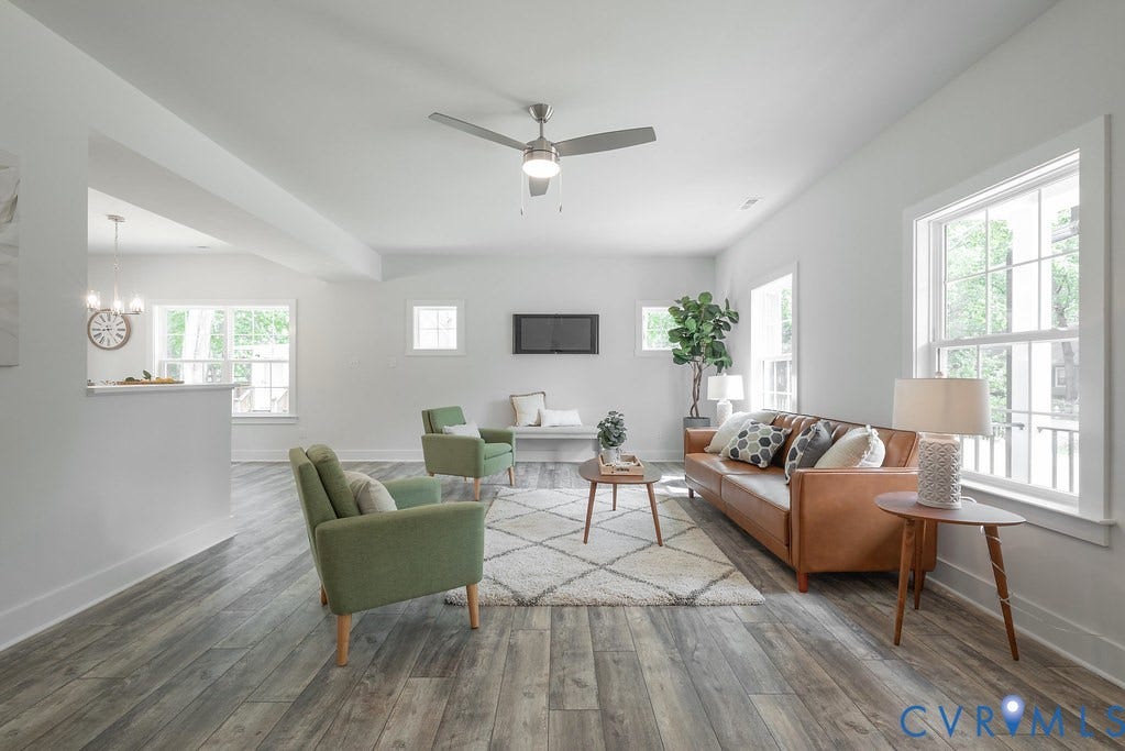 Spacious interior featuring wood-finish flooring, white walls, multiple windows, an overhead ceiling fan, and recessed lighting