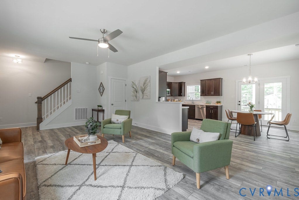 Open-concept living space featuring wood-finish flooring, a contemporary ceiling fan, and a kitchen with dark wood cabinetry