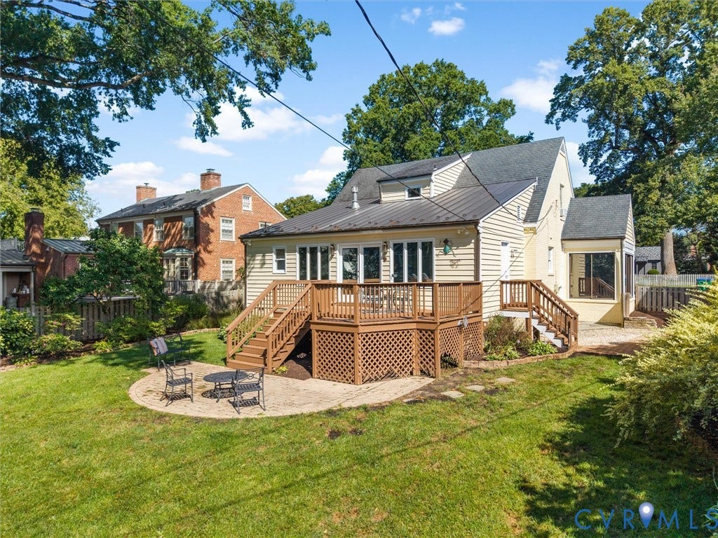Expansive backyard featuring a wood deck with lattice skirting, a concrete patio, and a manicured lawn