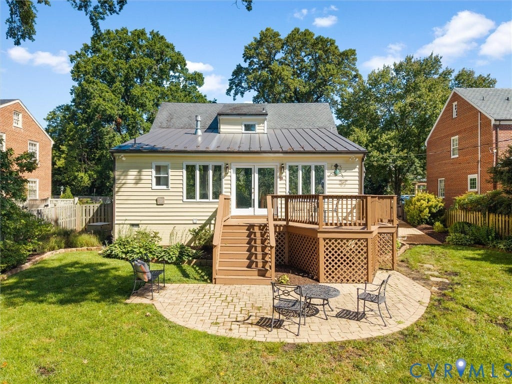 Rear exterior with light-colored siding, a metal roof, and a wood-finish multi-level deck