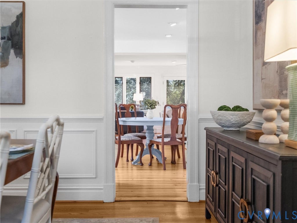 White paneled wainscoting with a wide trim, bright white wall paint, light wood-finish flooring, and a wide doorway