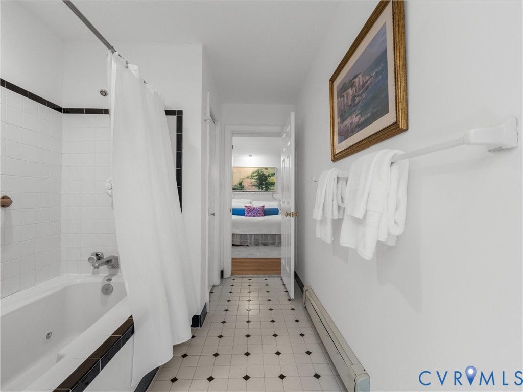Tile flooring with a contrasting pattern, white subway tile shower surround, and built-in soaking tub with dark trim