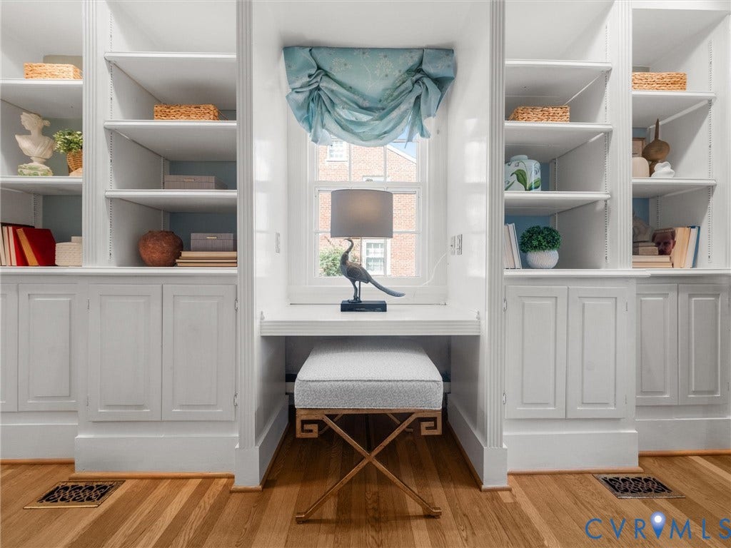 Built-in shelving with lower cabinetry, integrated desk space, and wood-finish flooring