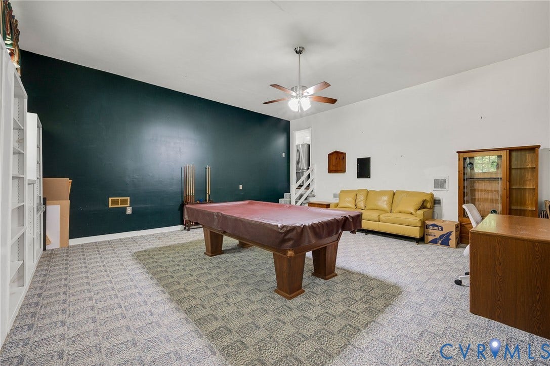 2409 Three Bridge Road, Rural, Powhatan, VA 23139 Spacious room featuring vaulted ceilings, a ceiling fan, patterned carpet flooring, a dark accent wall, and built-in shelving