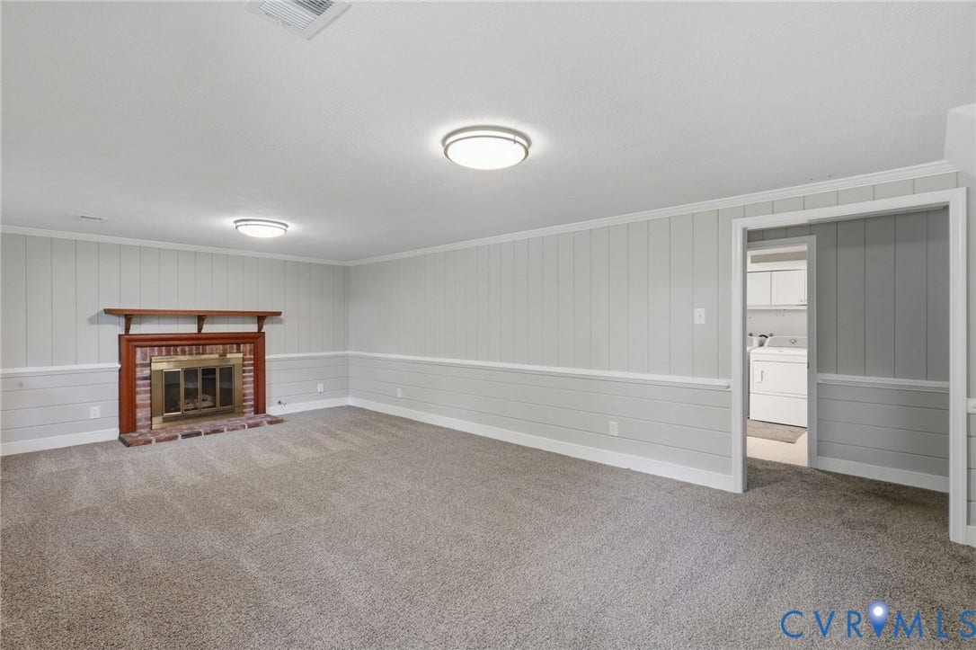 8349 Charlise Road, Oxford, Richmond, VA 23235 Spacious room featuring a brick fireplace with a wood mantle, carpet flooring, and board and batten wall detailing