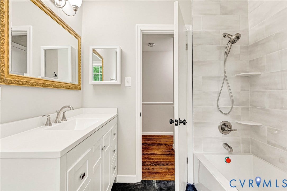 1605 CLOISTER Drive, Henrico, VA 23228 White vanity with integrated double sink, brushed nickel fixtures, subway tile shower surround, built-in shower shelving, and a combination showerhead and tub filler
