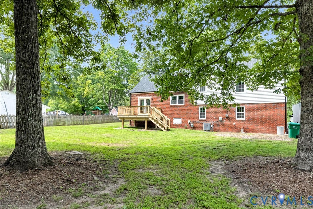 1605 CLOISTER Drive, Henrico, VA 23228 Expansive backyard featuring mature trees, a wood privacy fence, and a multi-level wood deck with steps