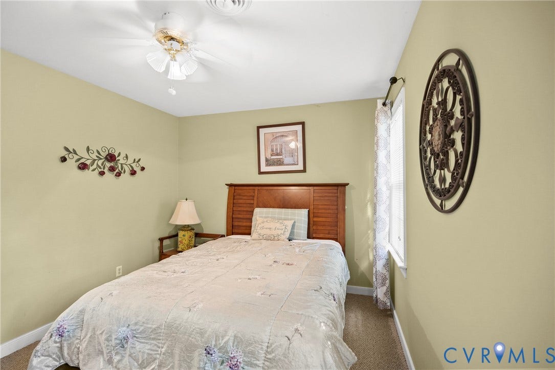 Recessed window, wood-finish headboard, built-in ceiling fan, and carpeted flooring