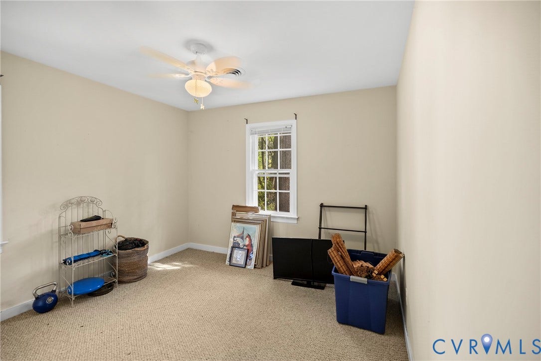 Carpeted room featuring a ceiling fan, a window with white trim, and neutral-toned walls