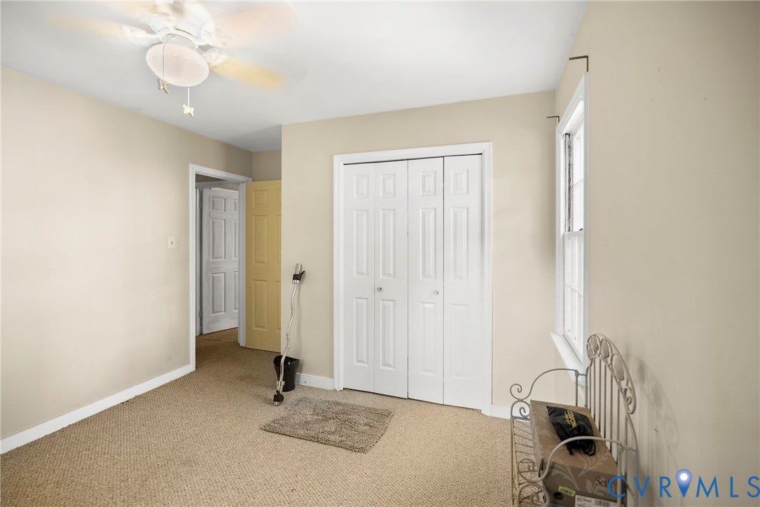 Carpeted flooring, bi-fold closet doors, ceiling fan with light fixture, natural light from window, and neutral wall tones