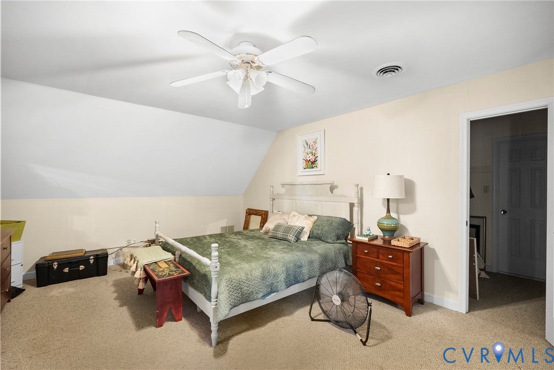 Carpeted room with an angled ceiling, ceiling fan, and a painted wood bed frame