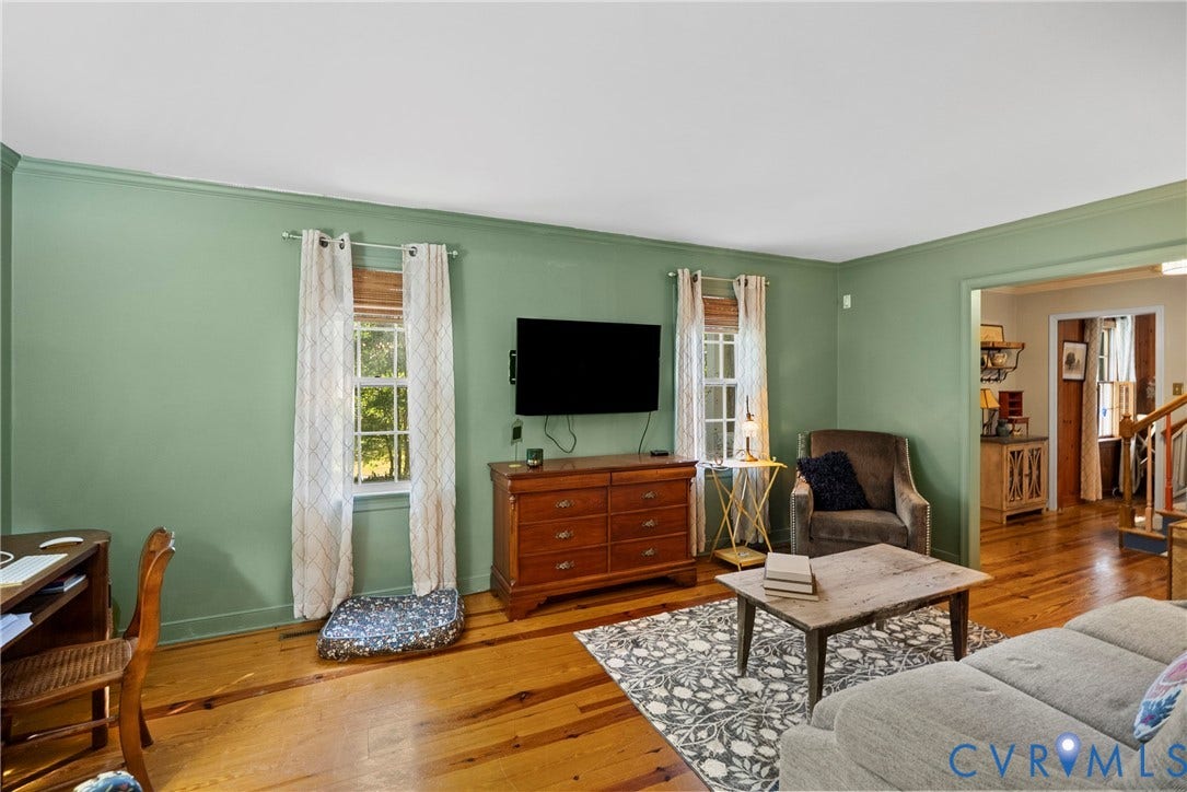 Wood-finish flooring, light green wall paint, white trim, and a wide interior doorway