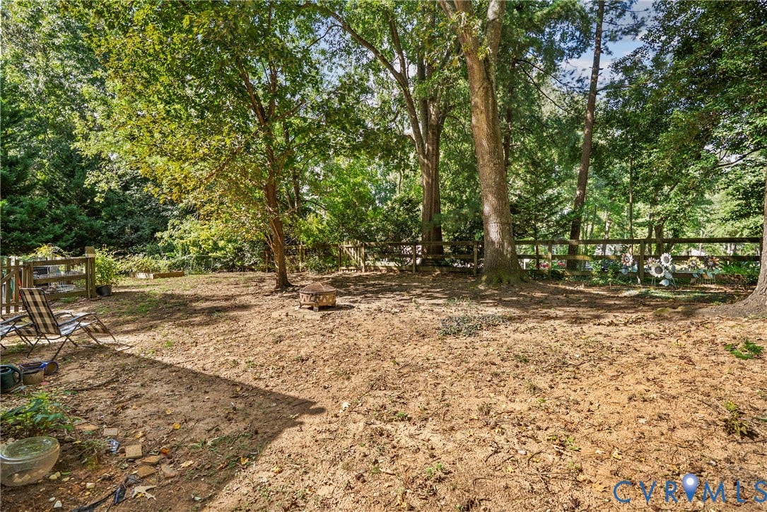 Expansive backyard area featuring mature trees and a wood fence border