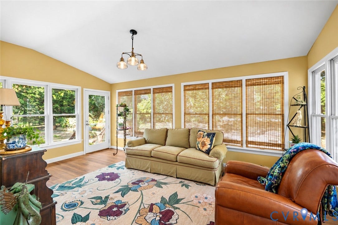 Vaulted ceiling, wood-finish flooring, abundant natural light, multiple windows, and a glass-paneled exterior door