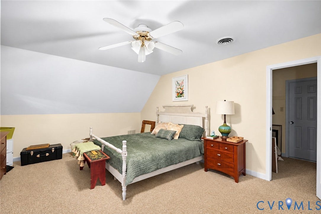 Carpeted flooring, sloped ceiling, ceiling fan with integrated lighting, and a white interior door
