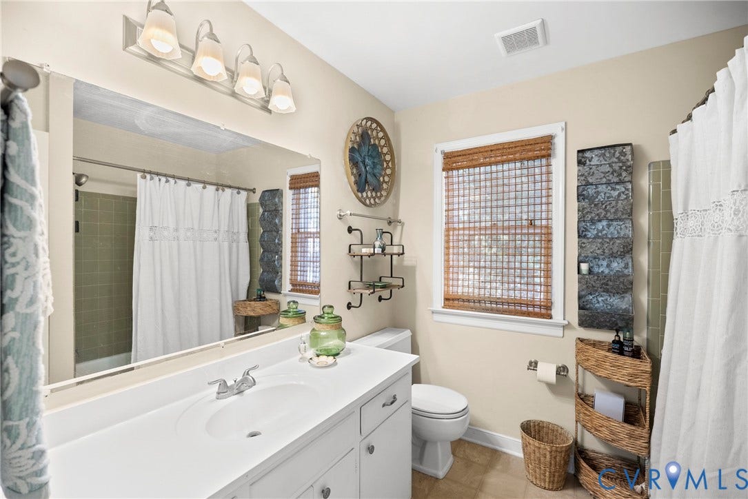 White vanity with an integrated sink and chrome faucet, full-width mirror, and five-light vanity fixture