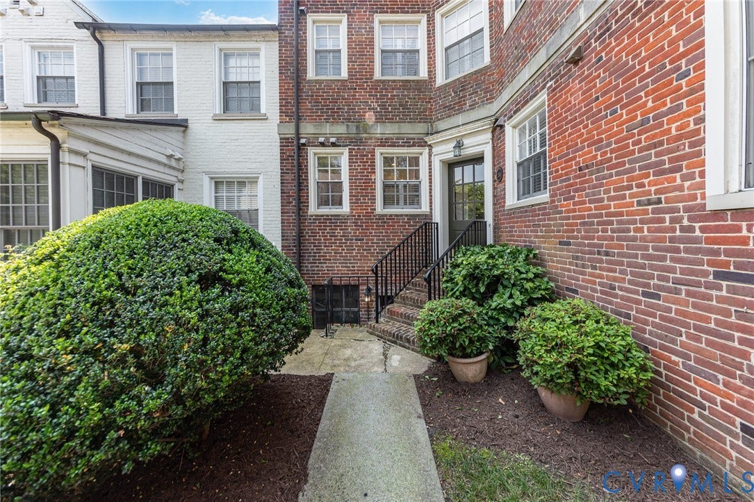 24 W Locke Lane, #1, Richmond, VA 23226 Brick exterior with multiple windows, a dark entry door, and a black iron handrail