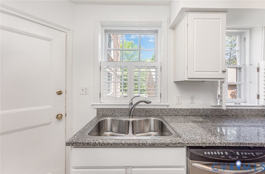 24 W Locke Lane, #1, Richmond, VA 23226 Stainless steel double basin sink with a gooseneck faucet, light granite-style countertops, white shaker-style cabinetry, and white window shutters