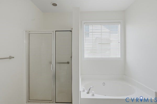 Recessed ceiling light, white walls, enclosed shower, corner soaking tub, and window with horizontal blinds